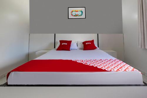 a bed with red pillows in a white room at OYO Hotel Sunshine in São Bernardo do Campo