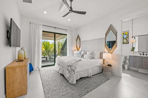 a white bedroom with a bed and a television at The Ringling Estate in Sarasota