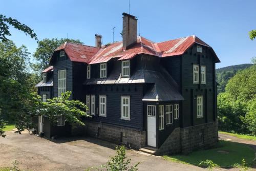 ein altes schwarzes Haus mit rotem Dach in der Unterkunft Château Josefův Důl in Josefův Důl u Jablonce nad Nisou