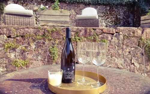 - une bouteille de vin assise sur une table avec deux verres dans l'établissement Le Moulin de L'O - L'Orle Rose, à Semur-en-Auxois