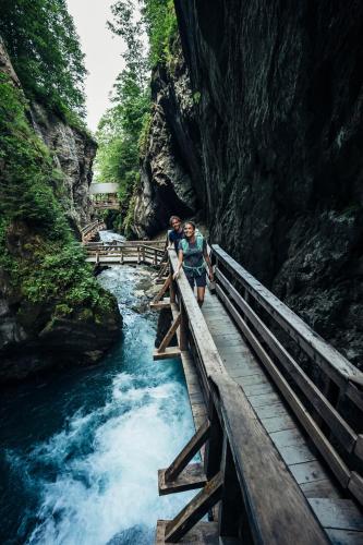 two people standing on a bridge over a river at Mountain View near Kaprun - Steinbock Lodges in Piesendorf