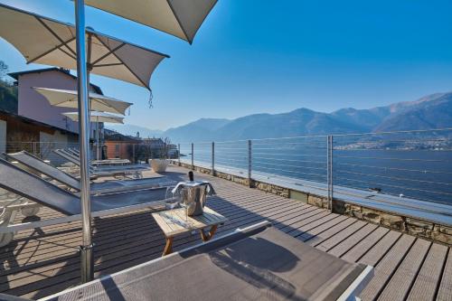 a deck with chairs and umbrellas on the water at Hotel Villa Aurora in Lezzeno