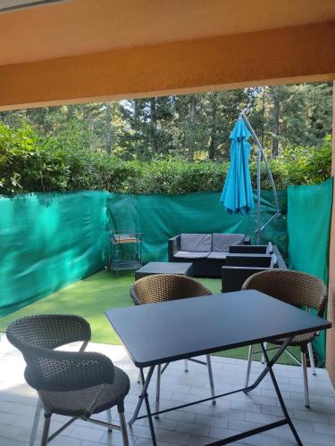 a patio with chairs and a table and an umbrella at STUDIO RDJ TERRASSE PISCINE SANARY SUR MER in Sanary-sur-Mer