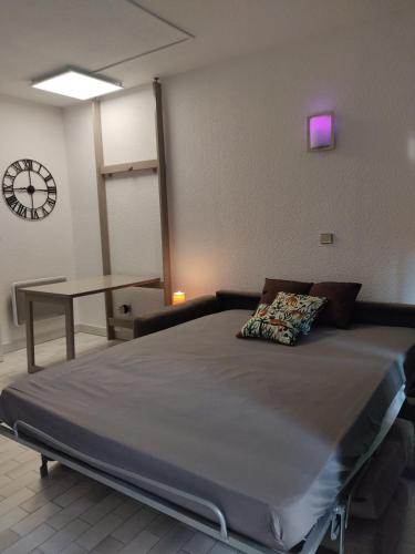 a large bed in a room with a clock on the wall at STUDIO RDJ TERRASSE PISCINE SANARY SUR MER in Sanary-sur-Mer