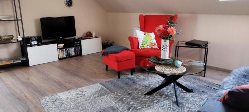 een woonkamer met een rode stoel en een tv bij Ferienwohnungen Meindl in Idar-Oberstein