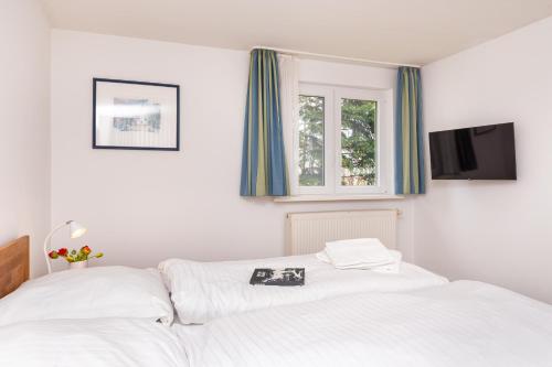 a bedroom with two white beds and a window at Das kleine Haus - Reetdachhaus Petersen in Nebel