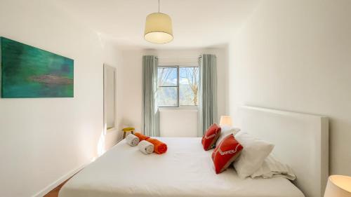 een slaapkamer met een wit bed met rode kussens bij Casa Varanda das Furnas in Furnas