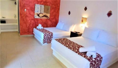 a hotel room with two beds and a table at Hotel Casa de las Flores in Playa del Carmen