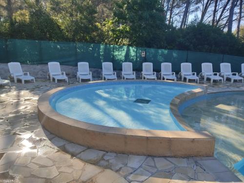 une piscine avec des chaises et un tas de chaises dans l'établissement STUDIO RDJ TERRASSE PISCINE SANARY SUR MER, à Sanary-sur-Mer