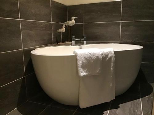 a bath tub in a bathroom with a bird on the wall at Fernbank in Shanklin