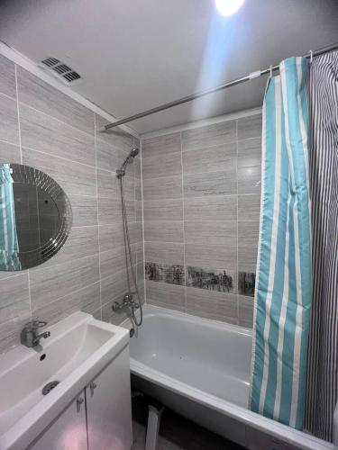 ein Badezimmer mit einer Badewanne, einem Waschbecken und einem Spiegel in der Unterkunft 2-х комнатная квартира напротив аквапарка in Aqtöbe