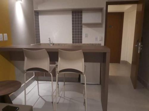 a kitchen with three white chairs and a counter at Olímpia Park Resort in Olímpia