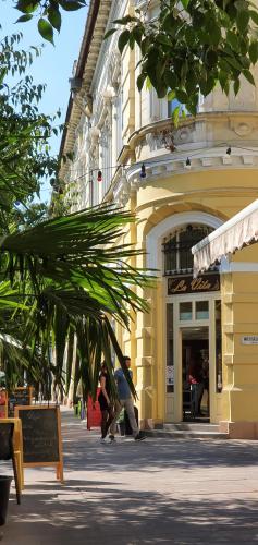 a large yellow building with people walking in front of it at MoMa Homes Kecskemét in Kecskemét