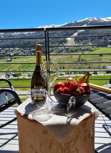 a table with a bowl of fruit and a bottle of wine at Vetta Alpine Relax in Livigno