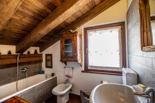 a bathroom with a tub and a sink and a toilet at L'Atelier du Temps - Chalet Les Marmottes in Cogne