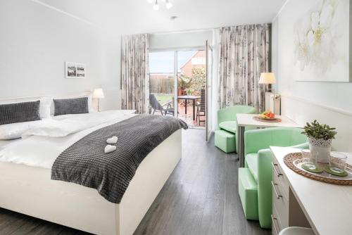 1 dormitorio con 1 cama, mesa y sillas en Hotel garni Haus am Meer en Neuharlingersiel