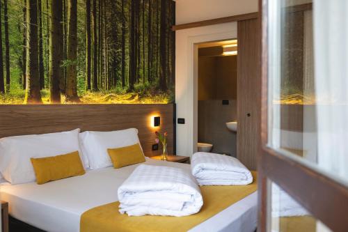 a bedroom with a bed with a forest mural on the wall at Hi Hotel - Wellness & Spa in Trento