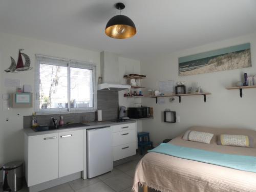 Cet appartement comprend une chambre avec un lit et une cuisine avec des placards blancs. dans l'établissement Grain de Sable et son Jacuzzi, à Talmont-Saint-Hilaire