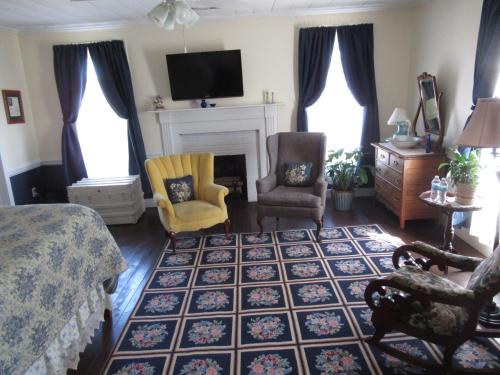 a bedroom with a bed and chairs and a fireplace at Carrier Houses Bed & Breakfast in Rutherfordton