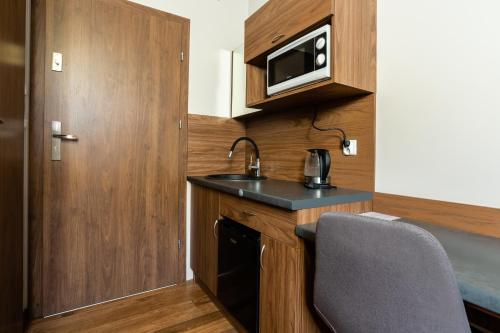 a small kitchen with a sink and a microwave at NoclegiJarocin Bed & Breakfast in Jarocin