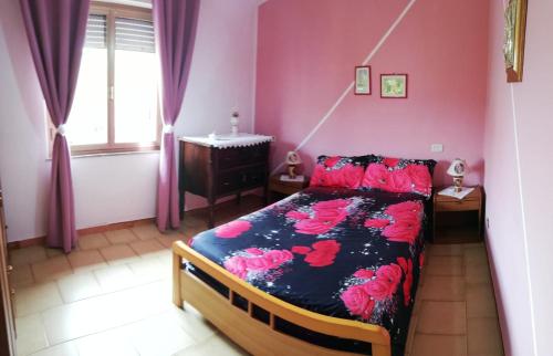 a bedroom with a bed with pink walls at nonna assunta in Teulada