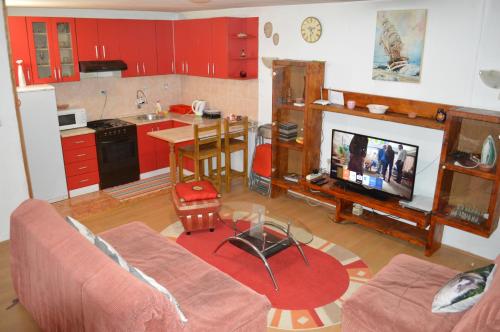 a living room with a couch and a kitchen with red cabinets at Apartman "Busije" in Požarevac