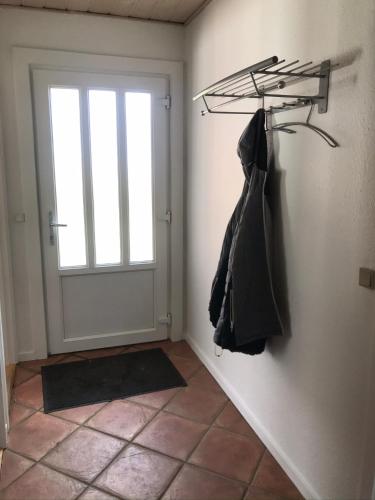 a room with a door and a coat hanging on a wall at Lille Røde hus Mandø in Ribe