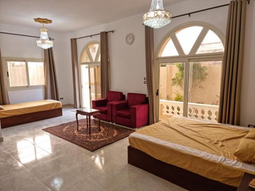 a bedroom with two beds and a chair and a window at فيلا العيلة Villa L-3eela in Abû Zeira