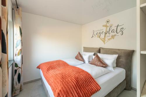 ein Schlafzimmer mit einem Bett mit einer orangefarbenen Decke in der Unterkunft Lakeside Resort Michaela in Antrifttal