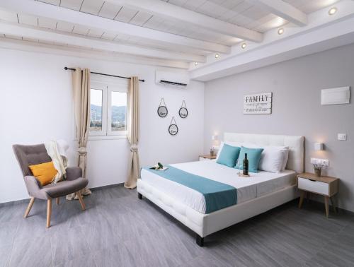 Ermis Luxury Suites & Apartments في أمودارا هيراكليو: غرفة نوم بيضاء بسرير كبير وكرسي