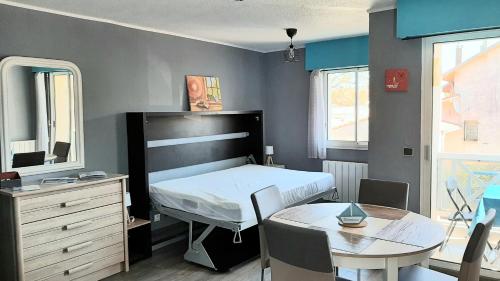 una camera con letto, tavolo, tavolo e specchio di Le Petit Bleu de Didonne 28m2 150 m de la plage avec balcon a Saint-Georges-de-Didonne