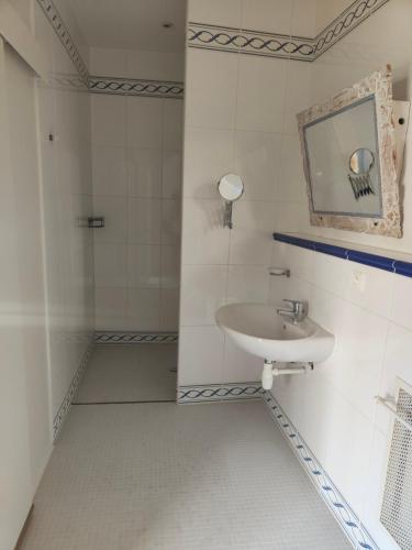 Baño blanco con lavabo y espejo en L'auberge De Thenay, en Thenay