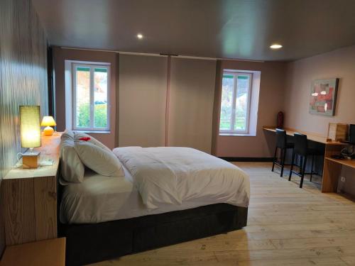 1 dormitorio con cama, mesa y ventanas en L'auberge De Thenay, en Thenay
