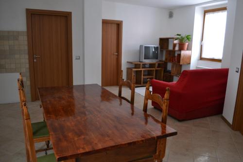 uma sala de estar com uma mesa de madeira e um sofá vermelho em Casa Ledro em Ledro