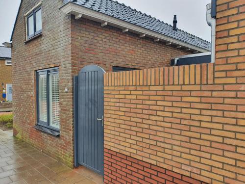 a brick house with a black gate and a brick fence at Knus huisje met prachtige nieuwe badkamer - Distelhoek in Egmond aan Zee