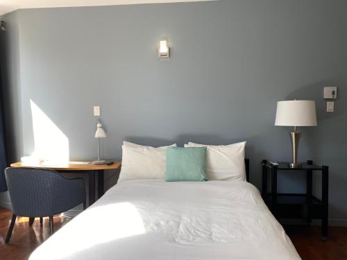 a bedroom with a white bed with a desk and lamp at Hotel Belley in Quebec City
