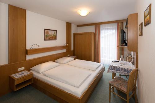 1 dormitorio con 1 cama, 1 mesa y 1 silla en Pension Schipflinger, en Saalbach Hinterglemm