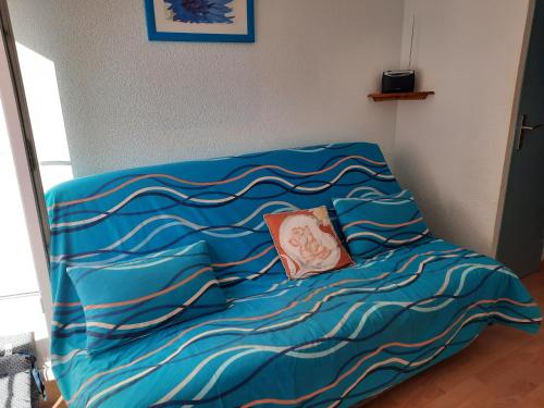 - un lit avec une couette bleue et un oreiller dans l'établissement studio tout équipé proche therme, à Lamalou-les-Bains