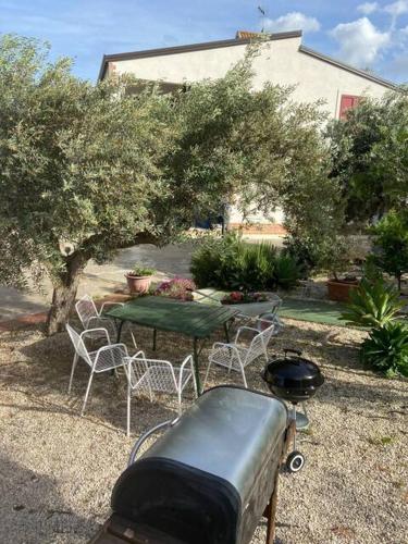 a table and chairs and a grill in a garden at La casa di Gioggiò in Ioppolo Giancaxio