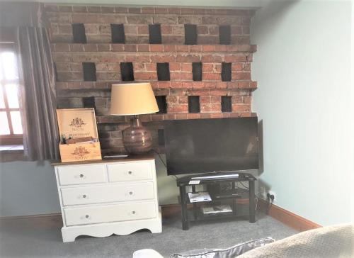 a living room with a brick fireplace and a television at The Carriage House, Studio 3A in Bilbrough