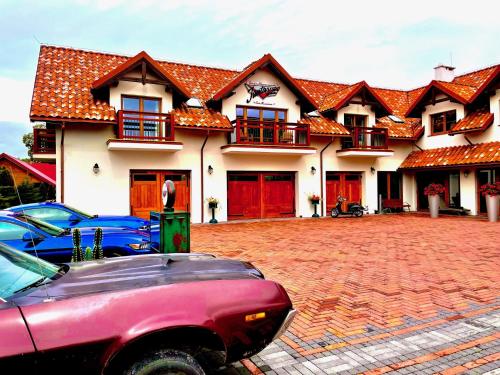a large house with cars parked in front of it at Jantarvia Car Museum , Pasja i Wypoczynek Noclegi z Klimatem in Jantar