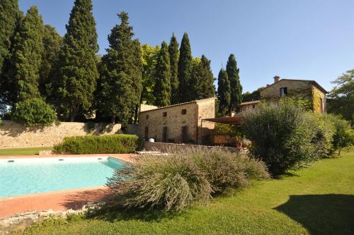 a swimming pool in front of a house with trees at Fattoria Lornano Winery in Monteriggioni