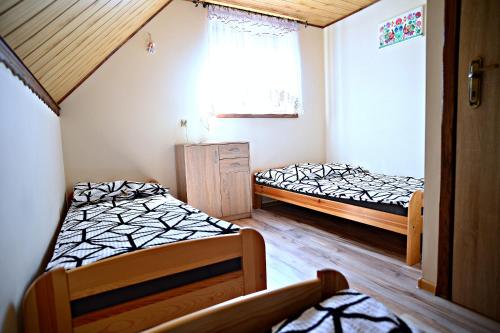 two beds in a small room with a window at Chata z Kominkiem - Drozdówka Solina- 6-9-2-2-8-1-3-6-3 in Solina