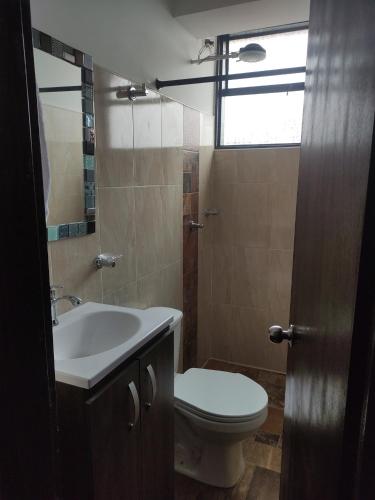 a bathroom with a toilet and a sink and a window at El buen descanso in Fusagasuga