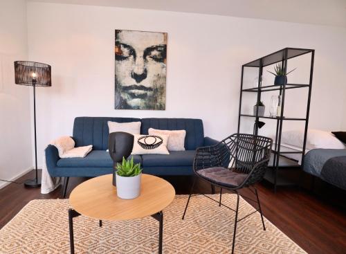 uma sala de estar com um sofá azul e uma mesa em SUNSET APARTMENT: FREE PARKING + BALCONY + NETFLIX em Essen