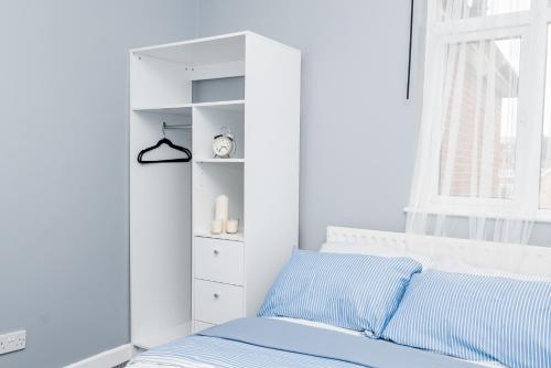 a white bedroom with a blue bed and a window at Shirley house 2, Self Catering Guest House, Self Check in, Smart locks, 10 min Walk to Southampton General, Aspire and Princess Anne Hospitals, Access to Fully Equipped Kitchen, Excellent Transport Links, Ideal for Longer Stays and Hospital Shifts in Southampton