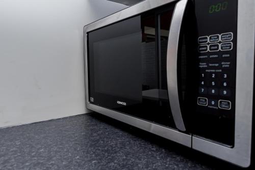a microwave oven sitting on top of a counter at Shirley house 2, Self Catering Guest House, Self Check in, Smart locks, 10 min Walk to Southampton General, Aspire and Princess Anne Hospitals, Access to Fully Equipped Kitchen, Excellent Transport Links, Ideal for Longer Stays and Hospital Shifts in Southampton