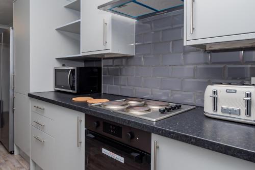 a kitchen with a stove top oven next to a microwave at Shirley house 2, Self Catering Guest House, Self Check in, Smart locks, 10 min Walk to Southampton General, Aspire and Princess Anne Hospitals, Access to Fully Equipped Kitchen, Excellent Transport Links, Ideal for Longer Stays and Hospital Shifts in Southampton