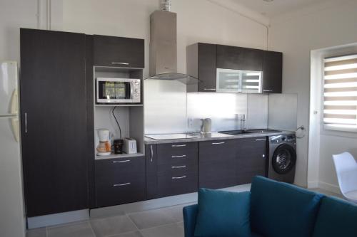 une cuisine avec des placards noirs et un canapé bleu dans l'établissement Villa à Golfe Juan, à Vallauris