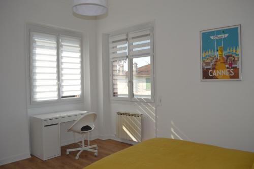 une chambre avec un lit et un bureau et deux fenêtres dans l'établissement Villa à Golfe Juan, à Vallauris